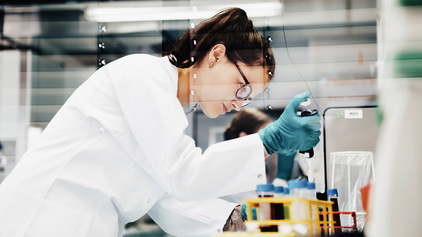 Kvinna i labbrock arbetar i laboratorium